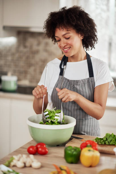 istock Woman mixing salad while standing in kitchen. 1179557314