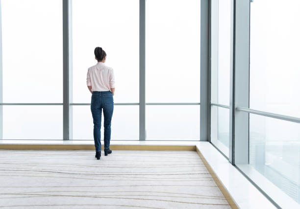 istock Businesswoman standing and looking through the window 1179557644