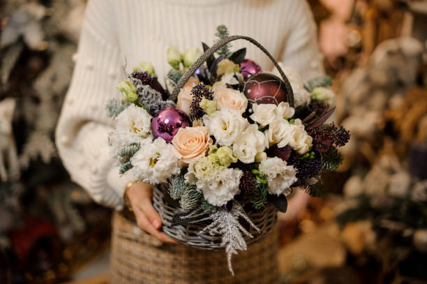 モミの木とクリスマスのおもちゃで飾られた白と桃の花と茶色のウィッカーバスケットを持つ女の子 - rose pink flower single flower ストックフォトと画像