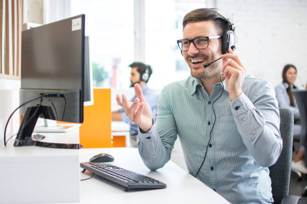 Happy handsome technical support operator with headset working in call centre Happy handsome technical support operator with headset working in call centre sales occupation stock pictures, royalty-free photos & images