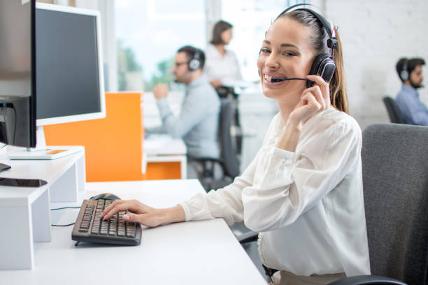 istock Friendly call center operator lady in wireless headset talking with customer in office 1179567407