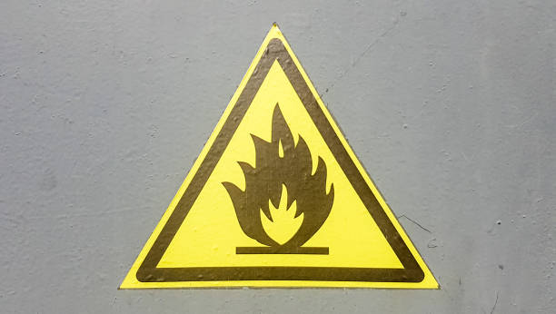 istock Fire warning icon, sign on a yellow label on a gray background. Flammable. Yellow triangle on a metal wall. Background with copy space 1179567455