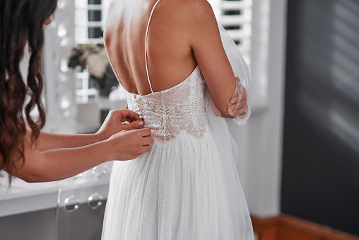 Cropped shot of an unrecognizable bridesmaid helping the bride get ready for her wedding ceremony