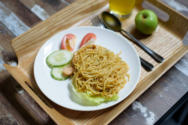 Image of Pesto Sauce Spaghetti with mix fruit juice and an apple on wooden table.