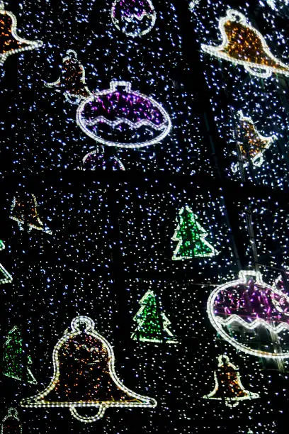 Modern lighting Christmas decorations at night,  festive motif adorns , bells, fir trees, balls, A Coruña townsquare, Galicia, Spain. Vertical view suitable for background purposes.