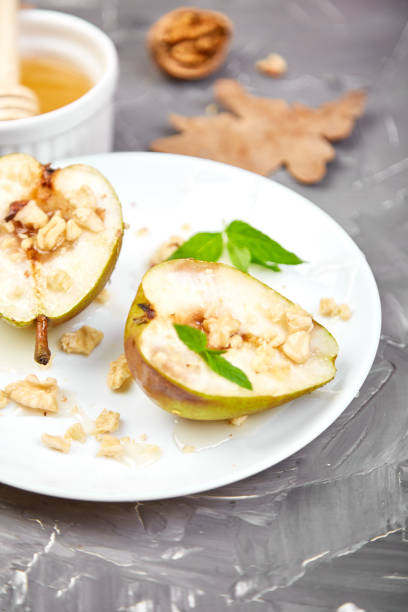istock Tasty roast pears with honey and walnuts on white plates on grey background table. 1179573660