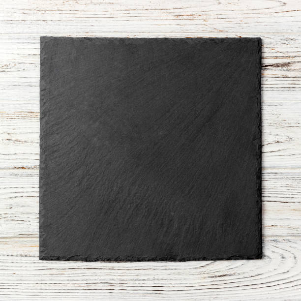 istock Black square plate on wooden background, top view, copy space 1179573758