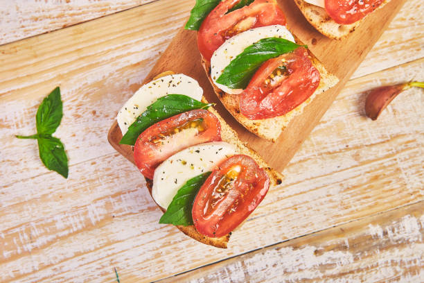 istock Caprese bruschetta toasts on a cutting board. Bruschetta with tomatoes, mozzarella cheese and basil on a rustic table. Traditional italian appetizer or snack, antipasto 1179573772
