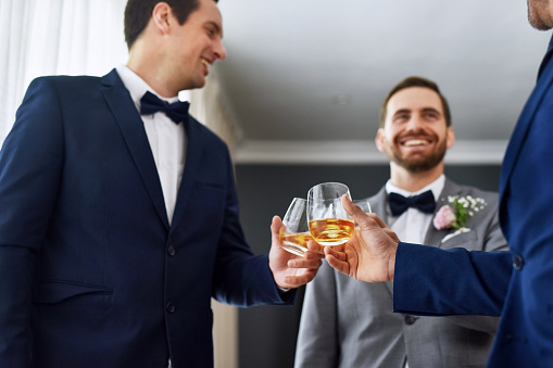 Shot of two unrecognizable groomsmen sharing a toast with the bridegroom on his wedding day