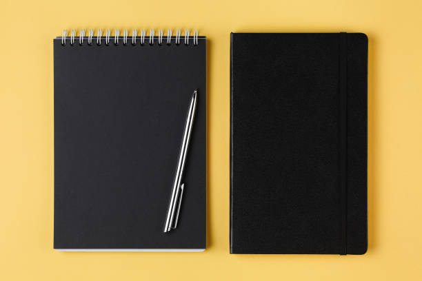 istock notebook with black paper and pen on a yellow background top view 1179582436
