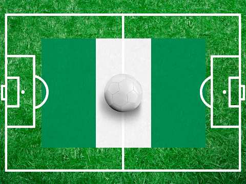Soccer ball with a flag of Nigeria on green grass and field Lines