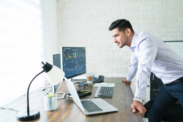 istock Male Trader Examining Share Market While Leaning On Desk 1179583803