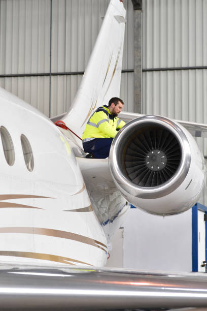 Airport workers check an aircraft for safety in a hangar Airport workers check an aircraft for safety in a hangar airplane maintenance stock pictures, royalty-free photos & images