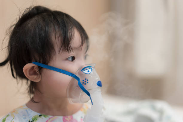 Little asian girl having a medical inhalation treatment with a nebulizer at the hospital. Close-up shot Little asian girl having a medical inhalation treatment with a nebulizer at the hospital. pediatric nebulizer mask stock pictures, royalty-free photos & images
