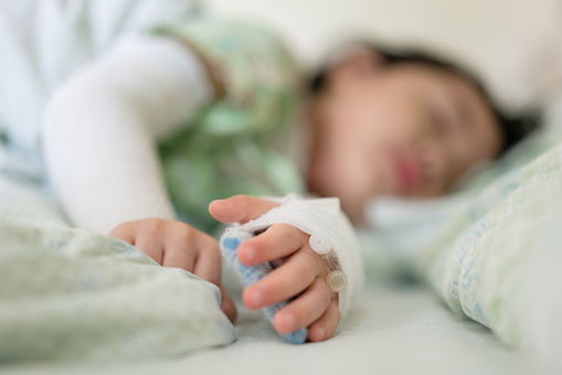 La pequeña asiática estaba enferma en la cama del hospital, niños de primer plano con la salmuera en el hospital. photo