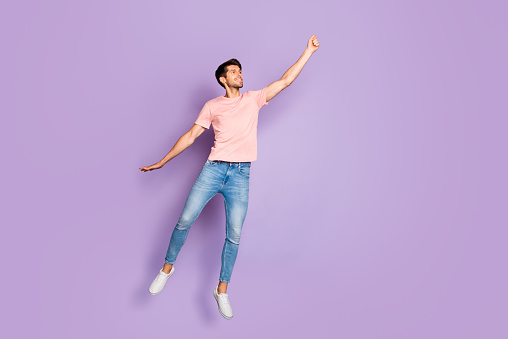 Full size photo of amazing guy jumping and flying high with imaginary, umbrella wear casual outfit isolated on purple color background