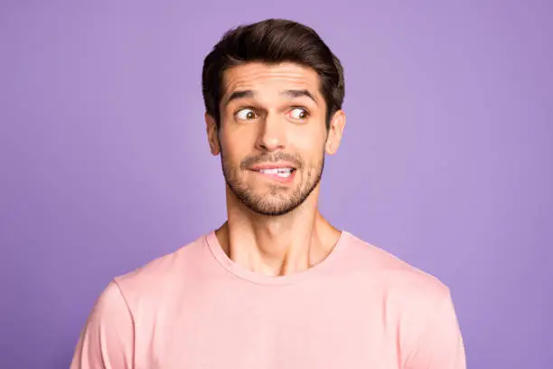 Close-up portrait of his he nice attractive funny confused brunet bearded guy wearing, pink tshirt waiting news biting lip isolated over violet purple lilac pastel color background