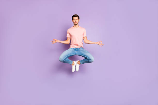 full length photo of amazing guy jumping in yoga practice exercises closing eyes wear casual outfit isolated on purple color background - om symbol fotos imagens e fotografias de stock