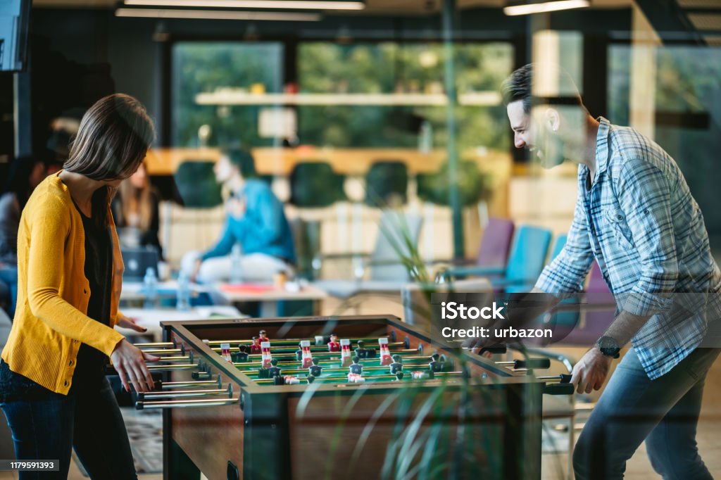 Foosball Break Two young Caucasian beautiful coworkers playing table football on break. Fun Stock Photo