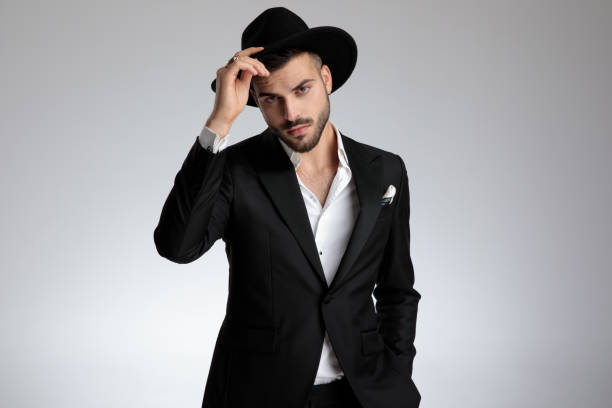 istock elegant young model holding hat and saluting on grey background 1179593101