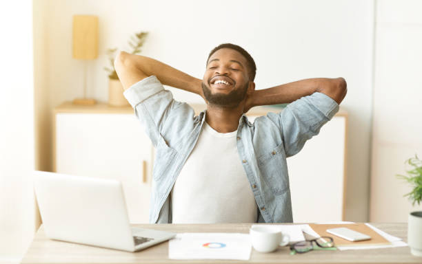 istock Happy afro worker leaning back in chair after successful workday 1179597678