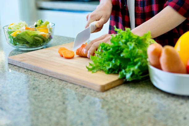 istock Woman cutting carrot on board in kitchen 1179598675
