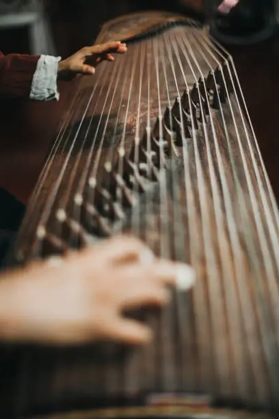 Close up of hands of a Chinese woman playing a zither, a traditional Chinese musical instrument