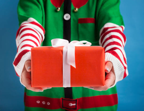 istock Santa's little helper holding holiday gift with ribbon on background 1179598951