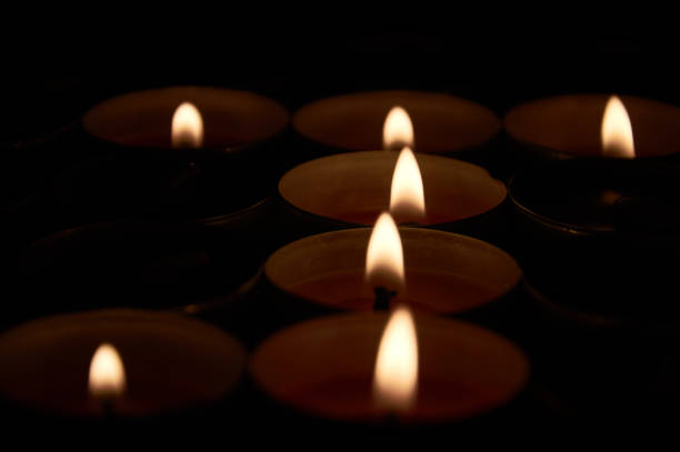istock Small flames of fire in several lit candles forming a J 1179599143