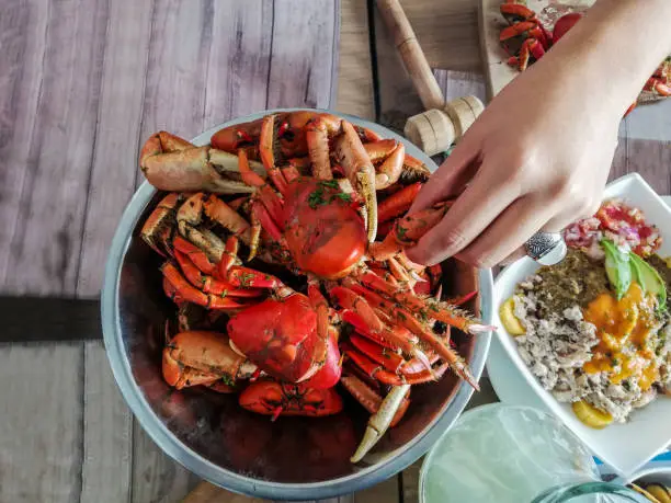 Aerial shot of a plate of crabs served in a bowl with one hand that will take a fat leg