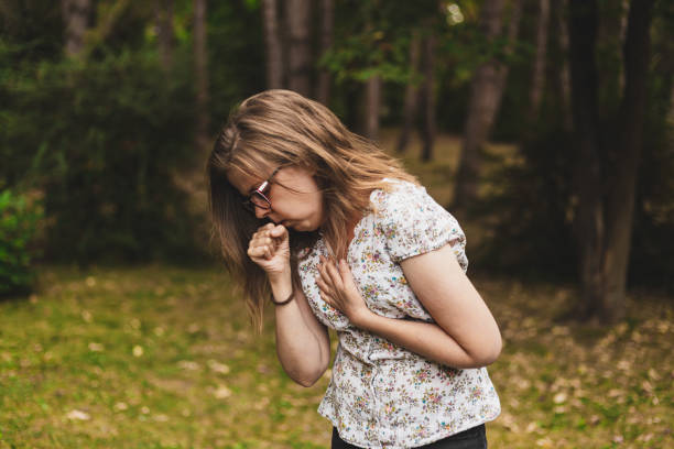 Woman coughing outdoors stock photo