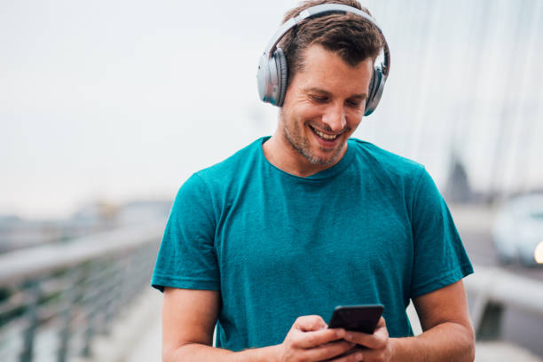 istock Young man with headphones and a smartphone walking on the bridge 1179599721