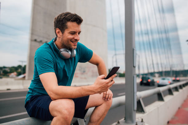 istock Young man sitting on the bridge and using his phone 1179599722