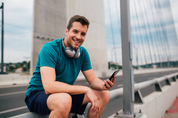 istock Young man sitting on the bridge and having fun online 1179599727