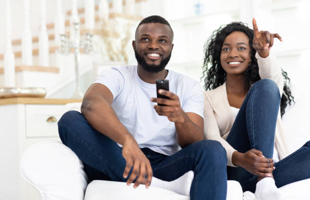 istock Black spouses watching tv together having fun at home 1179600298