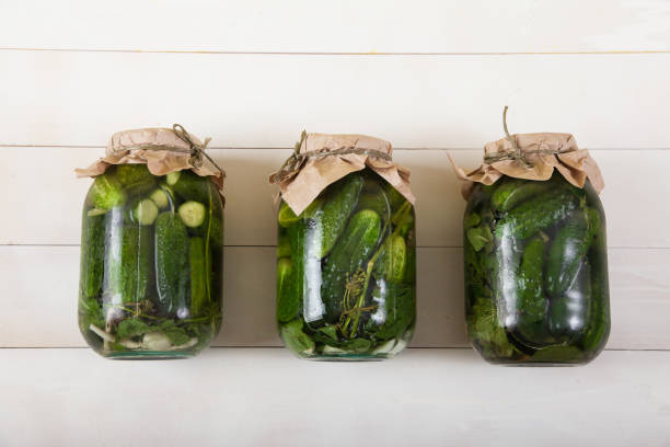istock Three large jars with fermented cucumbers lie on a white wooden background. 1179600341