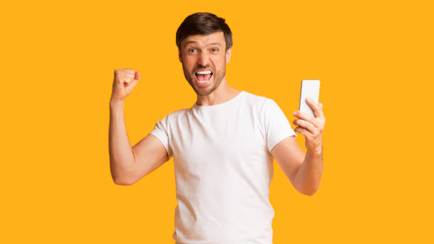 istock Emotional Guy Screaming Holding Cellphone Shaking Fists In Studio, Panorama 1179600655