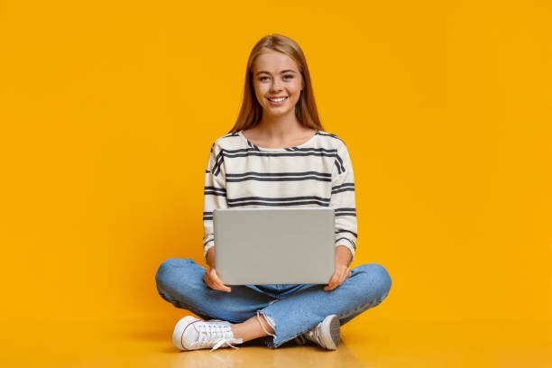 piękna młoda dziewczyna siedząca z laptopem na kolanach - yoga young adult cheerful happiness zdjęcia i obrazy z banku zdjęć