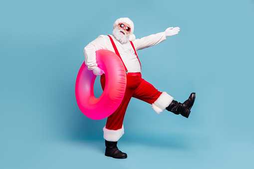 Full length body size view of his he nice cool cheerful cheery fat Santa walking carrying pink life buoy pool party isolated over blue turquoise pastel color background