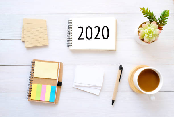 istock 2020 on notebook paper and blank notepad, organizer, businesscard, coffee, pencil on wood background, 2020 business new year mock up, template, flat lay 1179604335