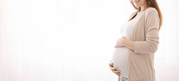 妊娠中の女性は彼女の腹を愛撫し、白いパノラマの背景 - abdomen adult affectionate baby ストックフォトと�画像