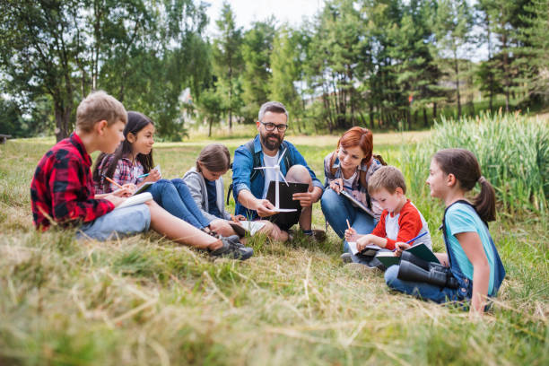 groupe d'enfants d'école avec le modèle d'enseignant et de moulin à vent sur l'excursion de champ dans la nature. - science education school offspring photos et images de collection