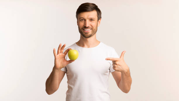 istock Man Pointing Finger At Apple In Hand, White Background, Panorama 1179604764