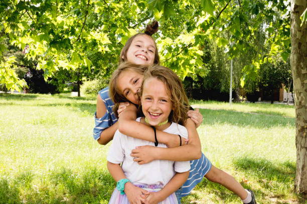 portret szczęśliwych uroczych sióstr dziewczynek w parku w słoneczny letni dzień - child laughing blond hair three people zdjęcia i obrazy z banku zdjęć