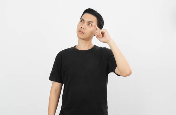 Young asian man with black shirt having doubts and with confuse face expression while scratching head on isolated on white background.