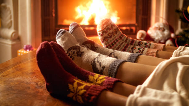 foto ravvicinata dei piedi di famiglia in calze di lana sdraiate accanto al camino - christmas home foto e immagini stock