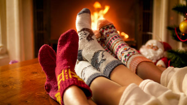famille utilisant les chaussettes tricotées chaudes détendant à la maison avec la cheminée brûlante - blanket fireplace winter women photos et images de collection