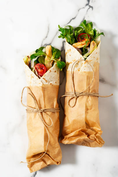 Fresh tortilla wraps on a marble patterned tabletop tied round with brown paper and string. stock photo