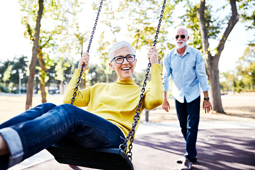 active senior couple enjoying  a swing in park