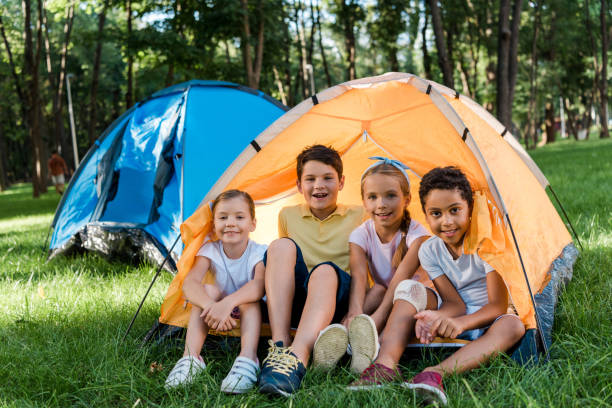 счастливые мультикультурные дети улыбаются, сидя в желтом лагере - preschooler plant multi ethnic group preschool стоковые фото и изображения